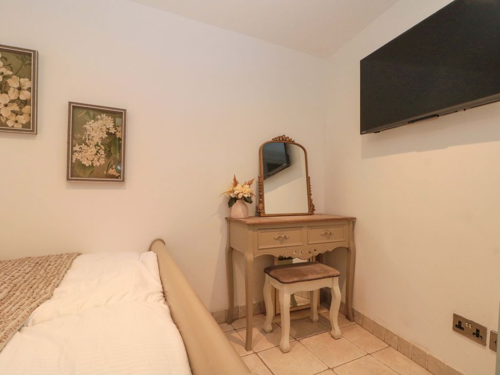 A bedroom with a bed and a dressing table at Rose Cottage in East Ayton