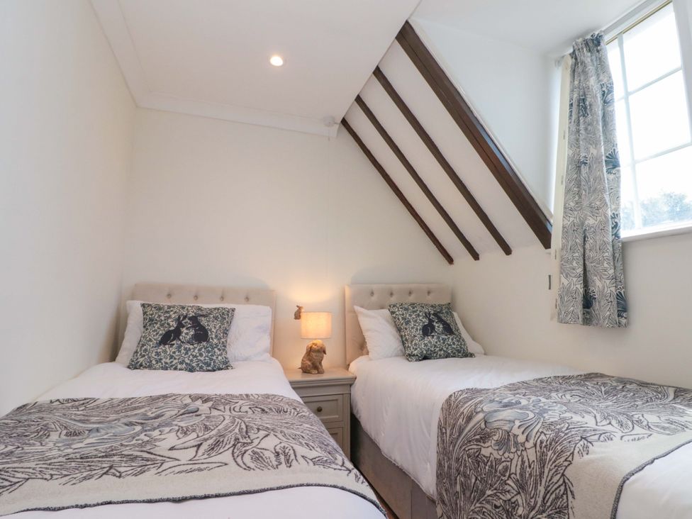 A bedroom with two beds and a bedside lamp at Rose Cottage in East Ayton