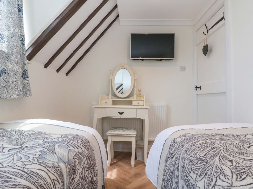 A bedroom with two beds and a vanity at Rose Cottage in East Ayton