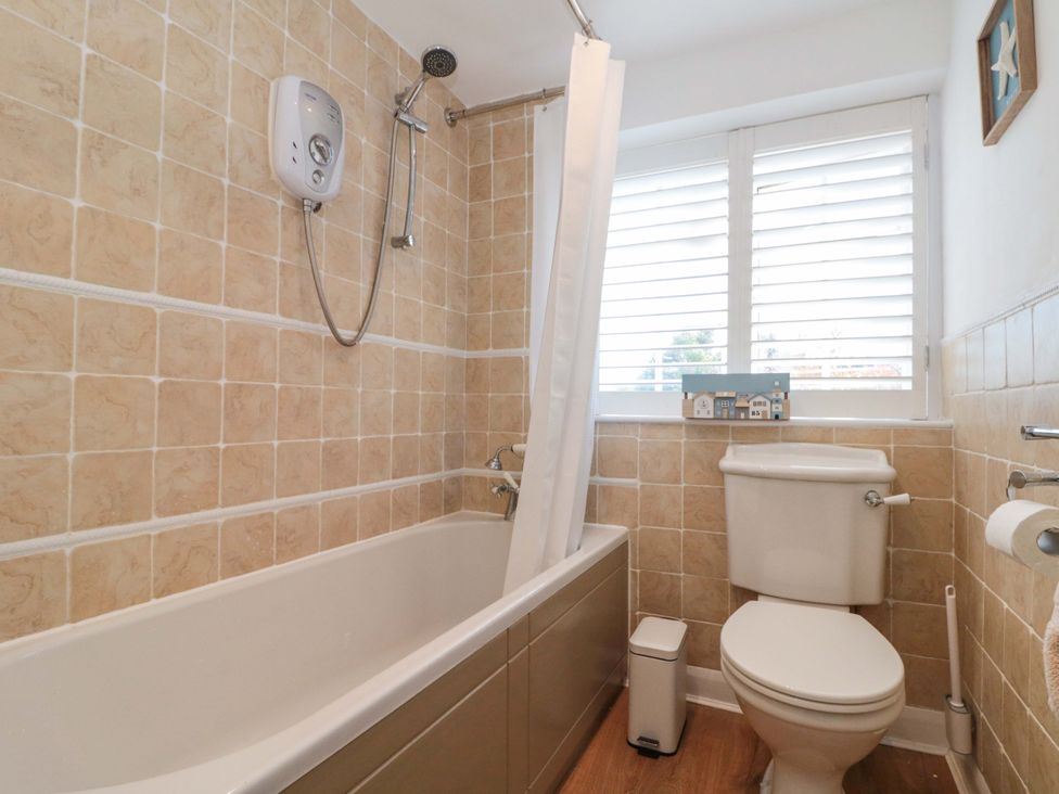 A bathroom with a bath tub and toilet at Rose Cottage East Ayton