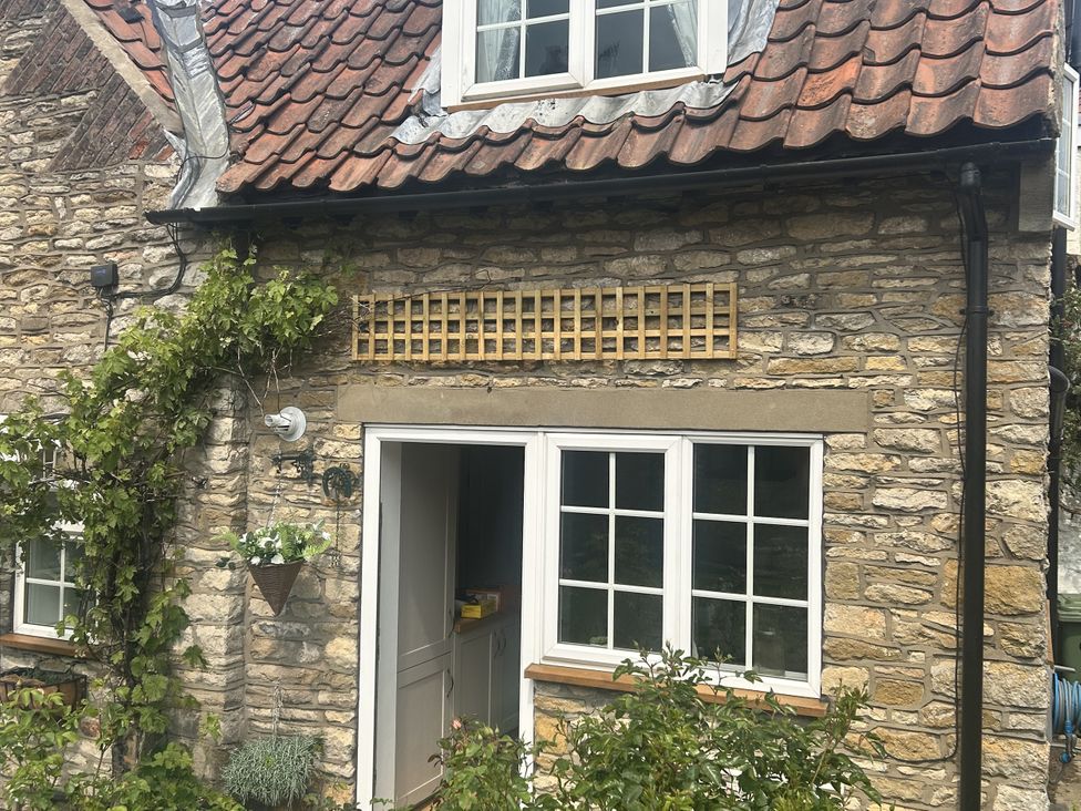 An exterior view of a stone wall with a window and door at Rose Cottage in East Ayton