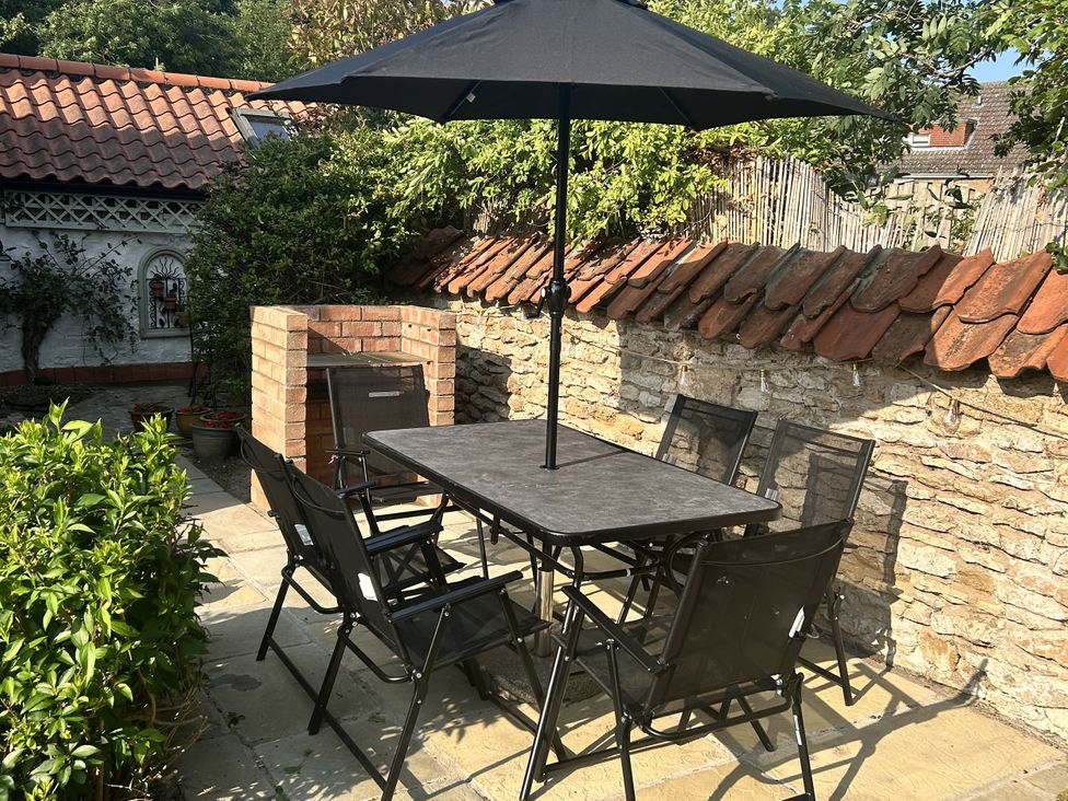 A garden with a table and chairs under an umbrella at Rose Cottage in East Ayton