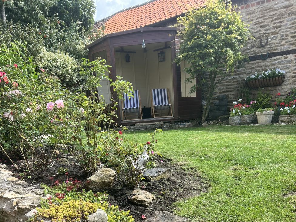 A garden with flowers and a wooden structure at Rose Cottage in East Ayton
