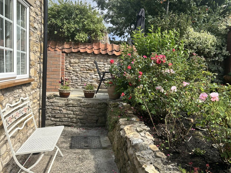 A garden with potted plants and a stone wall at Rose Cottage in East Ayton