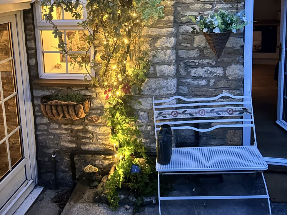 An outdoor area with a white bench and plant decorations at Rose Cottage in East Ayton
