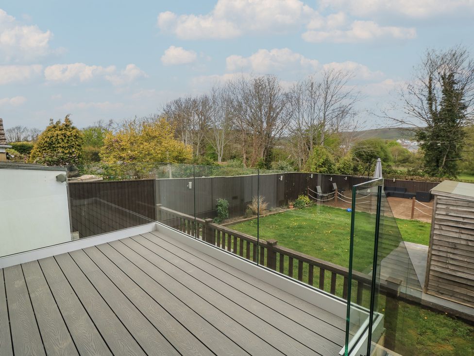 A deck with a glass railing overlooking a garden at The Swanage Rail Lookout in Swanage