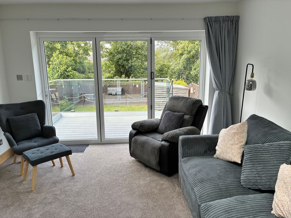A living room with a sofa and chairs and sliding doors at The Swanage Rail Lookout in Swanage