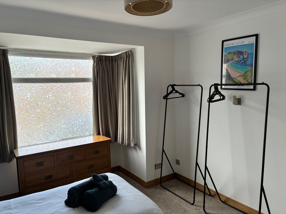 A bedroom with a window, dresser and clothes racks at The Swanage Rail Lookout in Swanage