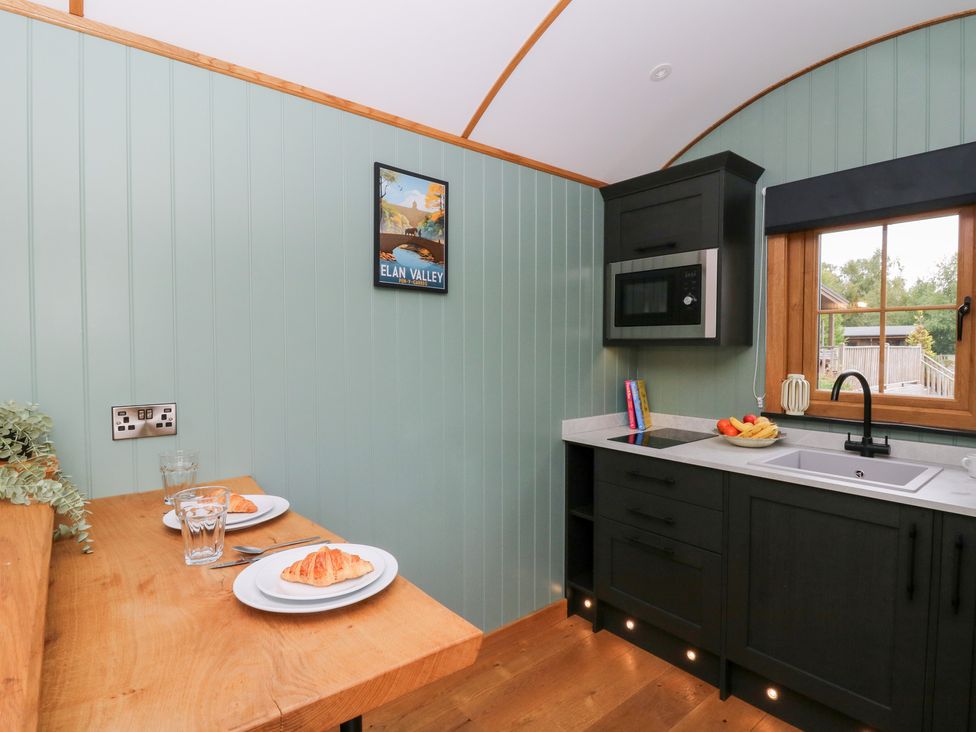 A kitchen with a table and plates at Dam View Shepherds Hut Upper Bwlch near Rhayader
