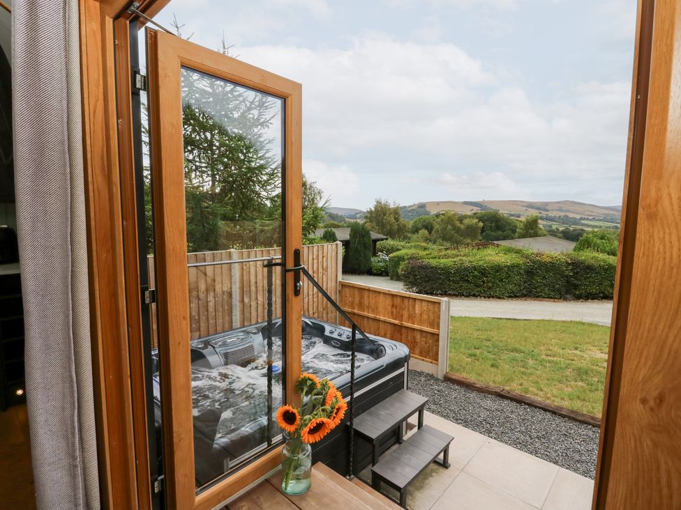 A view through a doorway showing a hot tub and flowers at Dam View Shepherds Hut Upper Bwlch near Rhayader