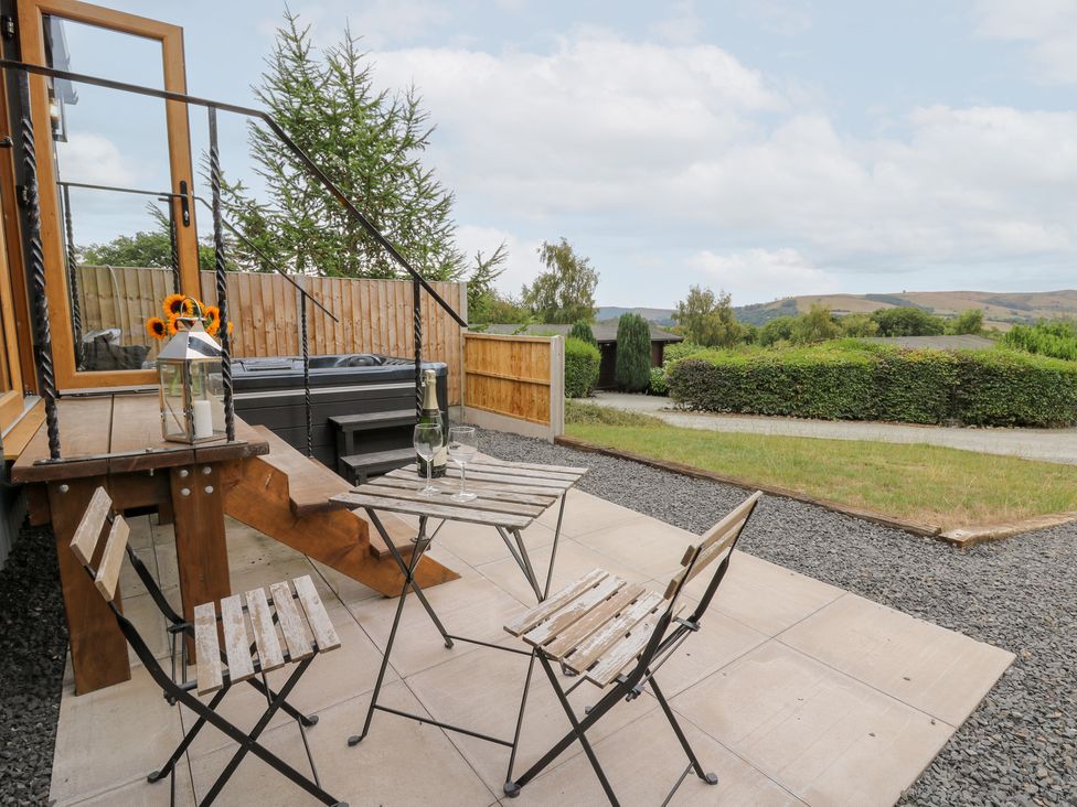 An outdoor patio with a table and chairs at Dam View Shepherds Hut Upper Bwlch near Rhayader