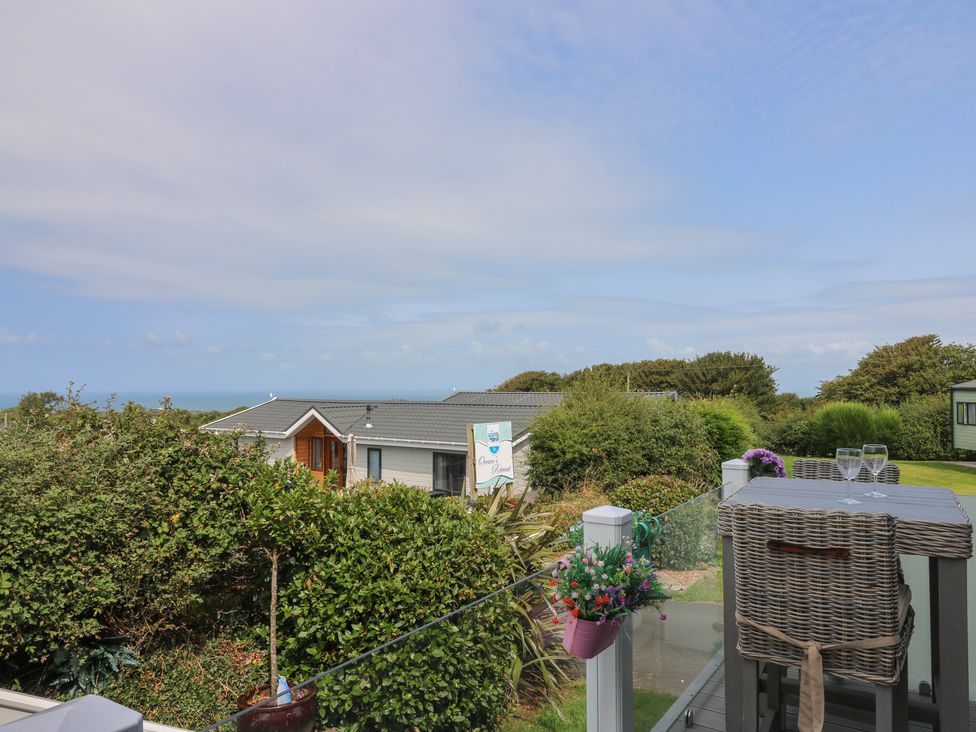 An outdoor area with table and chairs overlooking the ocean at Coogee View in Maenygroes near New Quay