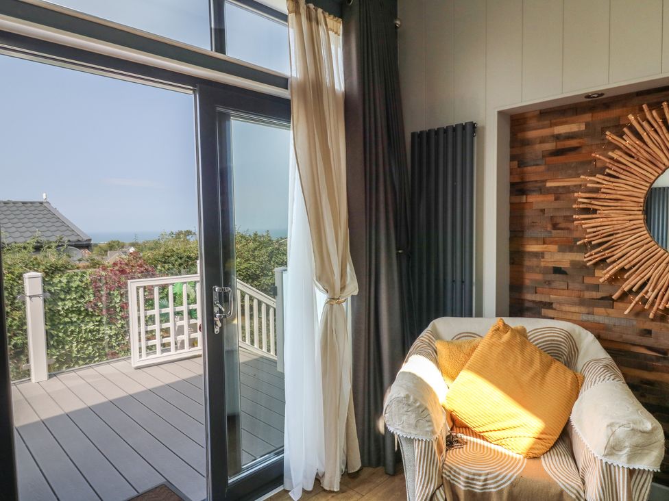 A snug with a chair and door leading to the outside at Coogee View in Maenygroes near New Quay