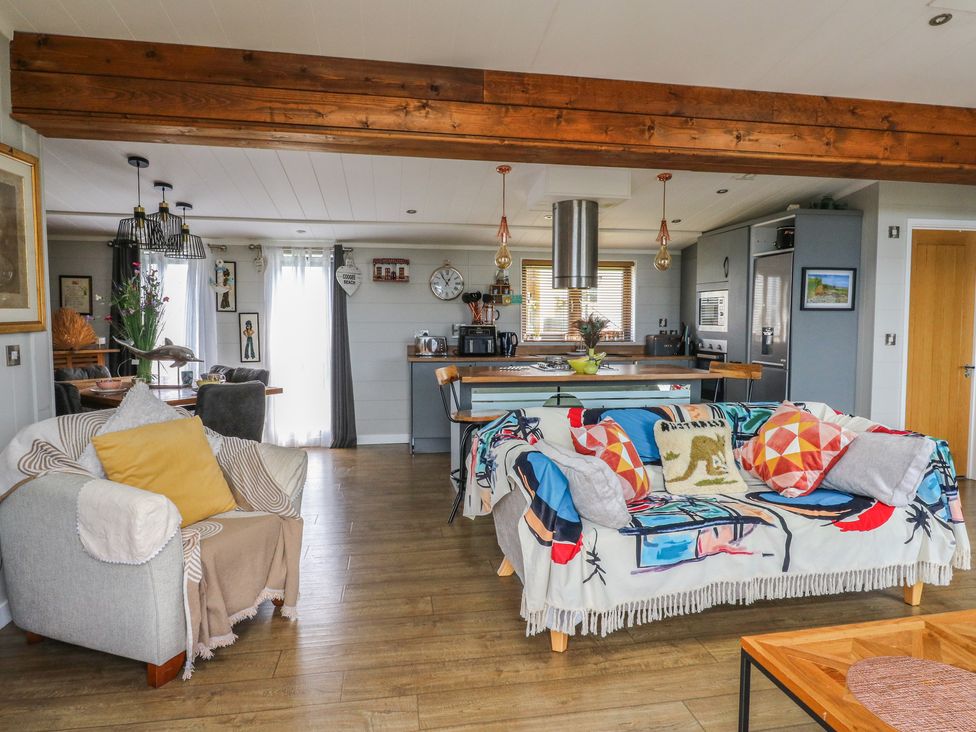 A living room with a sofa and kitchen island at Coogee View in Maenygroes near New Quay