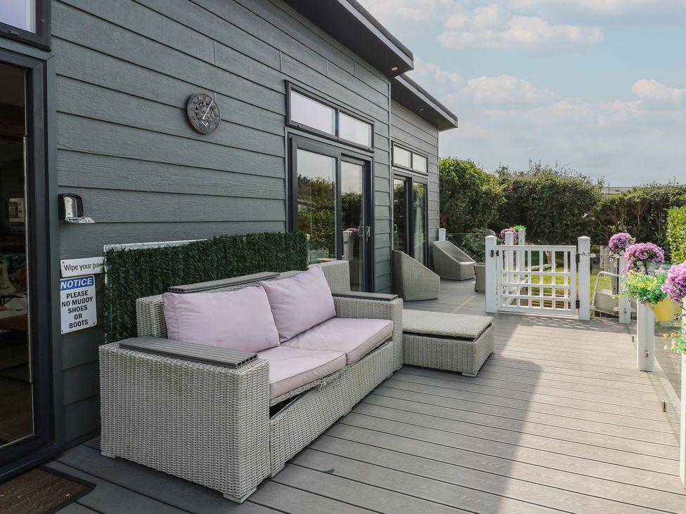 An outdoor area with a sofa and lounge chairs at Coogee View in Maenygroes near New Quay