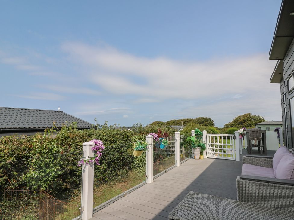 A deck with outdoor furniture and flowers at Coogee View in Maenygroes near New Quay