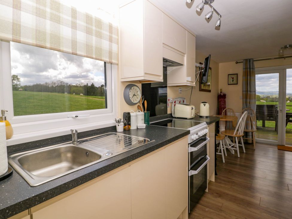 A kitchen with a sink stove toaster dining table and chairs overlooking a grassy field at Poppy in Raglan
