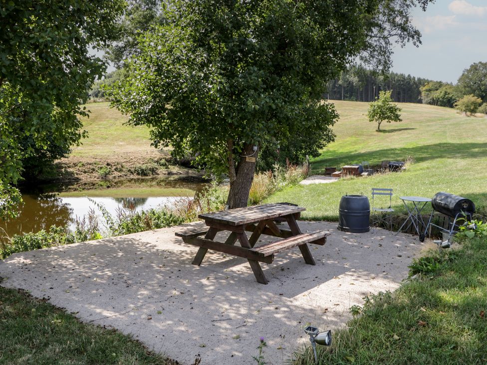 An outdoor area with picnic table and barrel near the water at Poppy in Raglan