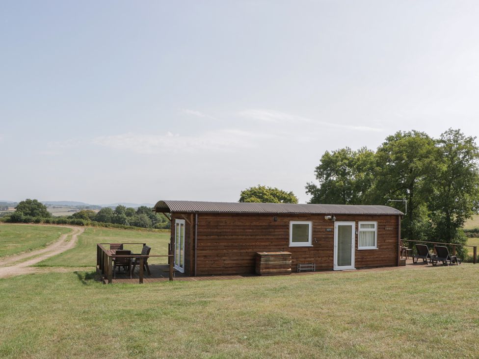 A wooden building with a deck and furniture at Poppy in Raglan
