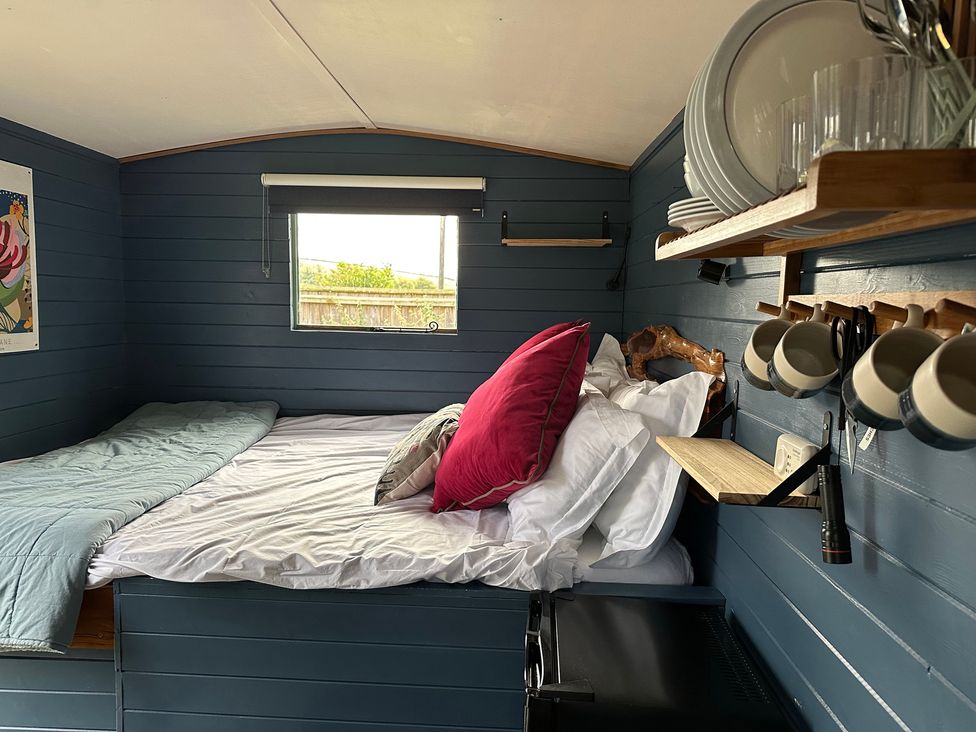 A bedroom with a bed, shelf, and window at Acres Meadow in Maiden Newton