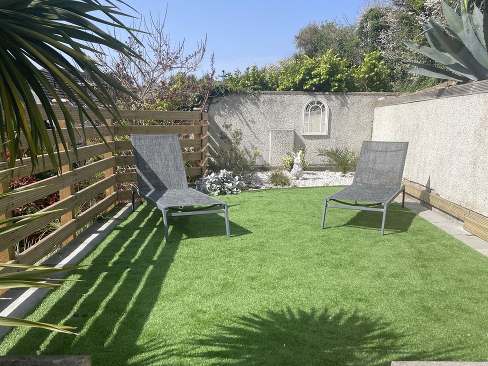 A garden with sun loungers and a landscaped area at Tidal View in Newquay
