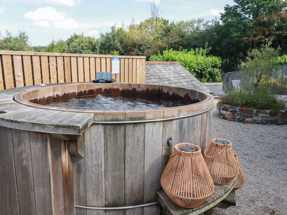 An outdoor area with a hot tub and wooden fence at Stable Loft in Watergate Bay