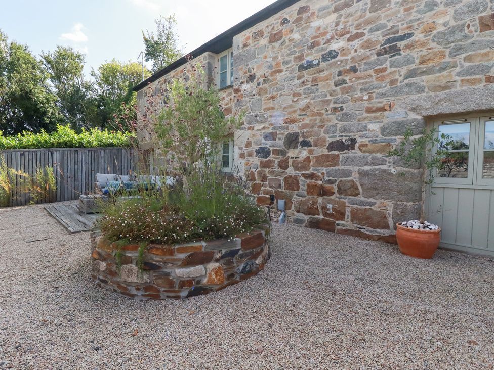 An outdoor area with a stone wall and a planter at Stable Loft Watergate Bay
