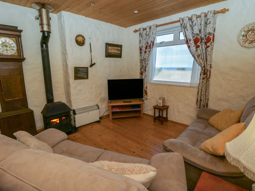 A living room with a clock, stove, and television at Harbour High Annex in Fishguard