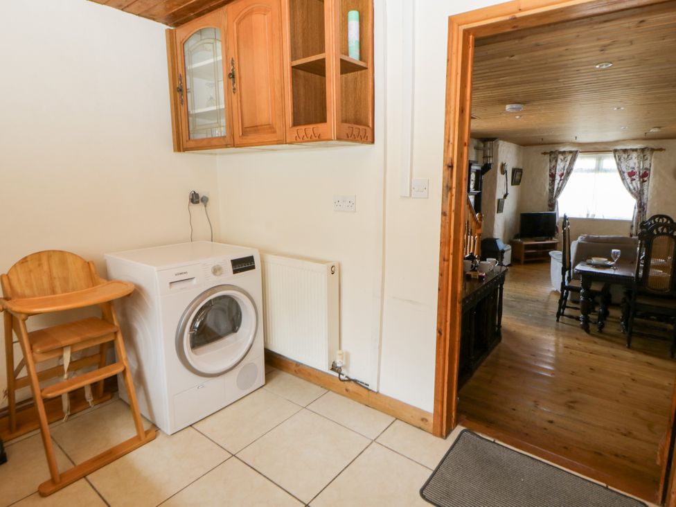 A kitchen with a washer and high chair at Harbour High Annex in Fishguard