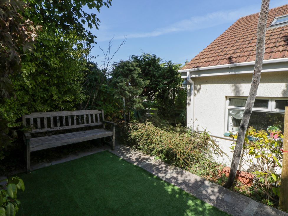 A garden with a wooden bench and plants at Harbour High Annex Fishguard