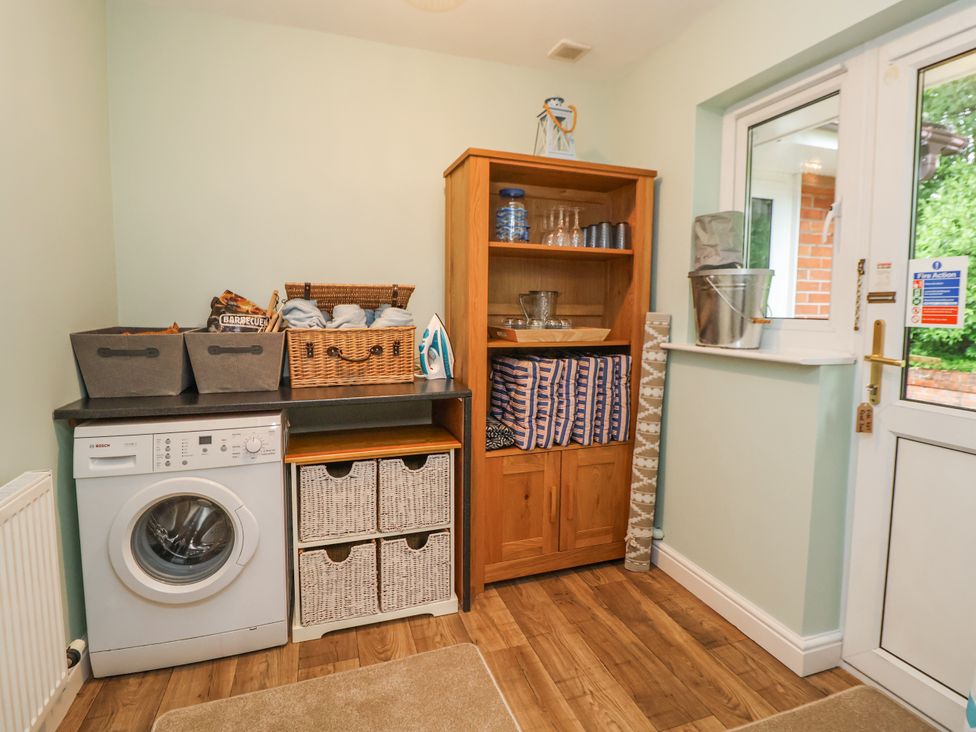 A laundry room with a washing machine and storage baskets at 2 Mountain View in Chirk