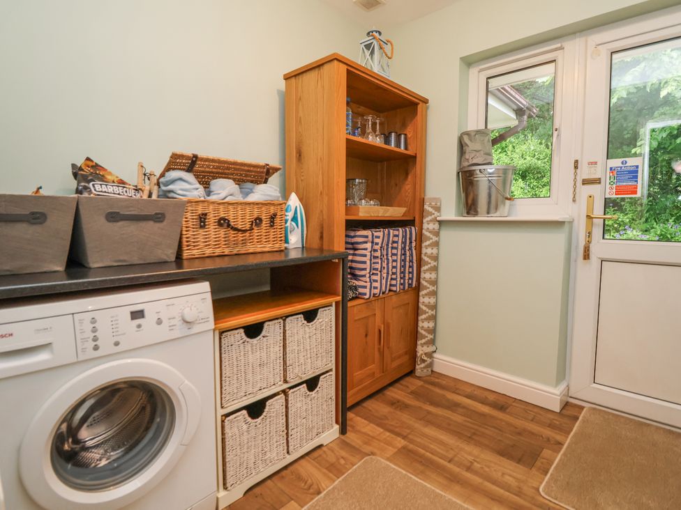 A laundry room with a washing machine and bookshelf at 2 Mountain View in Chirk