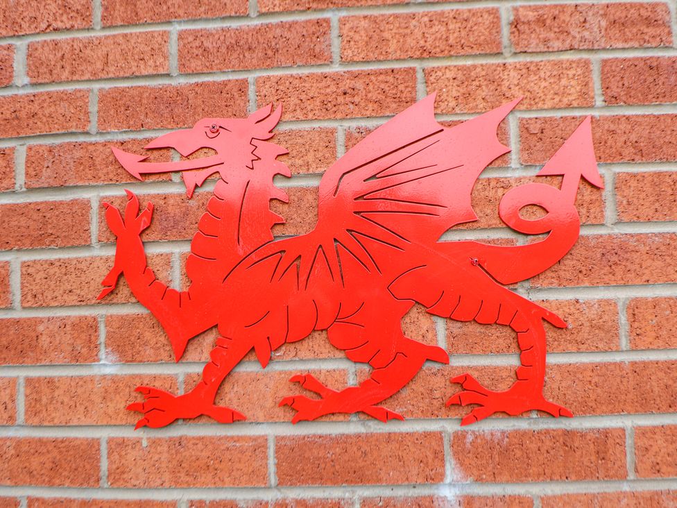 A red dragon mounted on a brick wall at 2 Mountain View Chirk