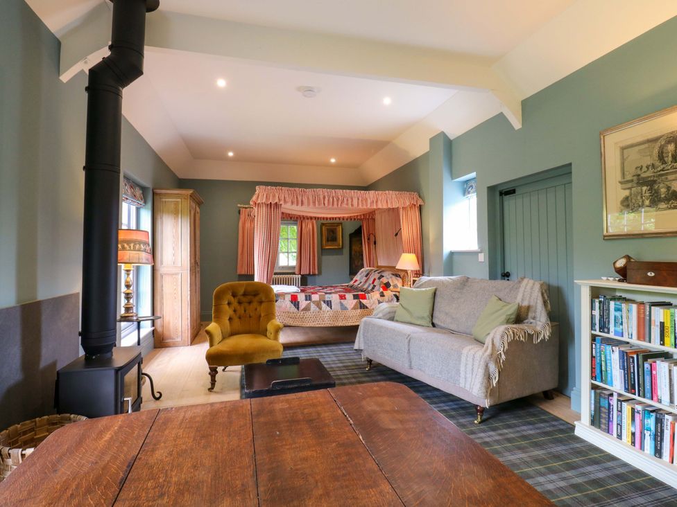 A living room with a sofa, armchair, and wooden cabinet at Clock Tower in Stowmarket