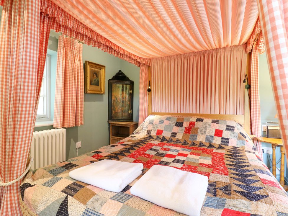 A bedroom with a canopy bed and quilt at Clock Tower in Stowmarket