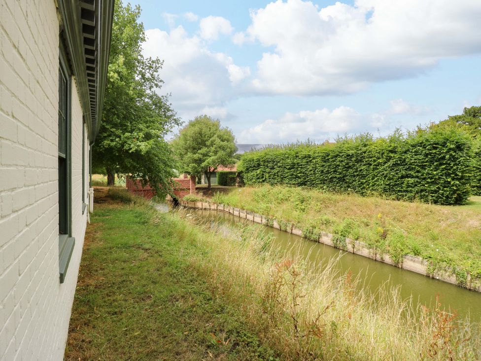 A view of a canal with grass and trees beside a building at Clock Tower in Stowmarket
