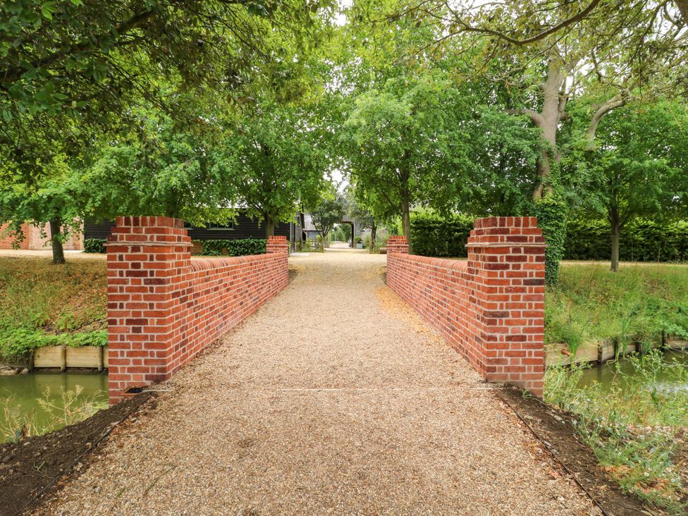 A pathway with a brick wall and trees at Clock Tower in Stowmarket