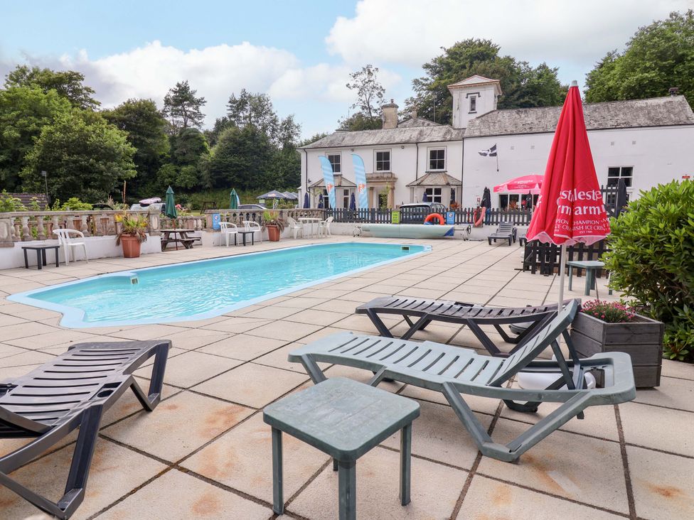 An outdoor swimming area with loungers and tables at Driftwood - 54 Valley Lodge St Ann's Chapel, Cornwall