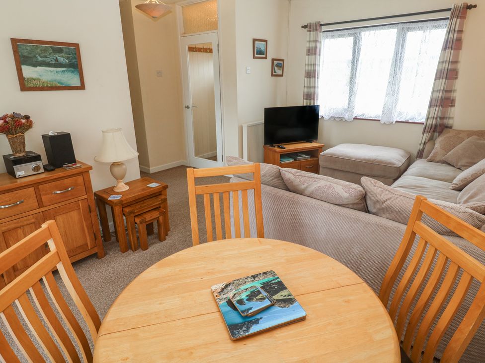 A living room with a sofa, dining table, and television at 14 Bosvigo Ruan Major near Penhale