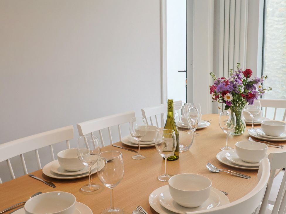 A dining table with plates and glasses at Wagtail Cottage in Lyme Regis