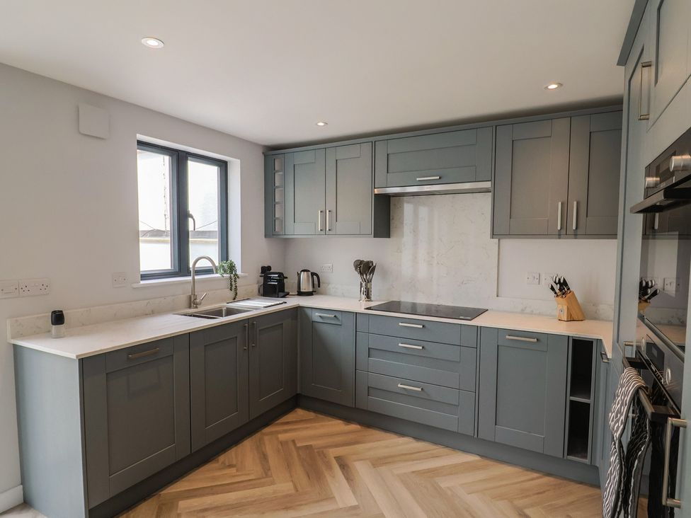 A kitchen with cabinets, sink and window at Wagtail Cottage in Lyme Regis
