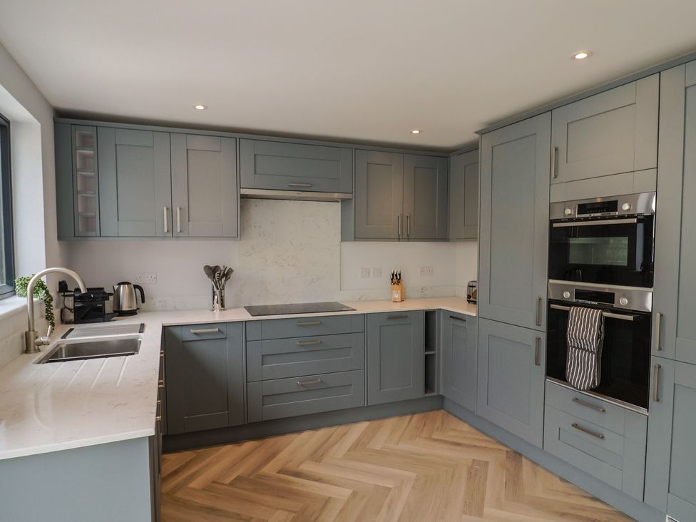 A kitchen with cabinets, sink, ovens, and utensils at Wagtail Cottage in Lyme Regis