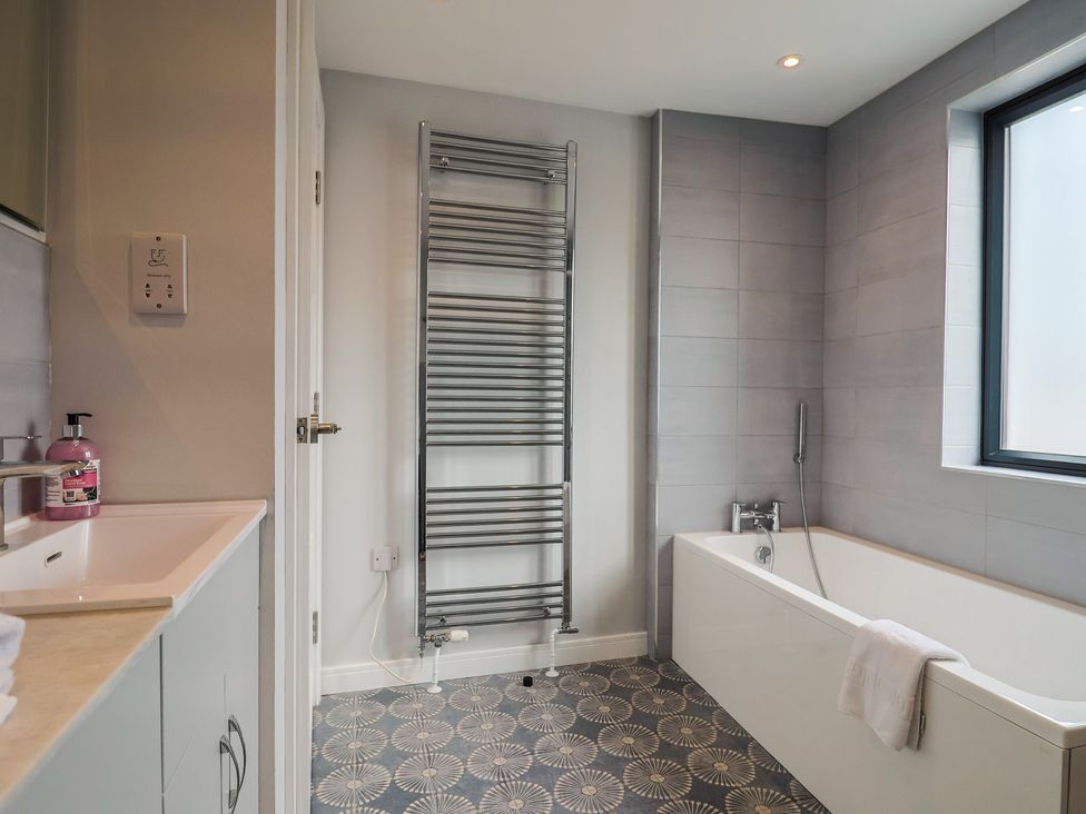 A bathroom with a bath tub and towel rail at Wagtail Cottage in Lyme Regis