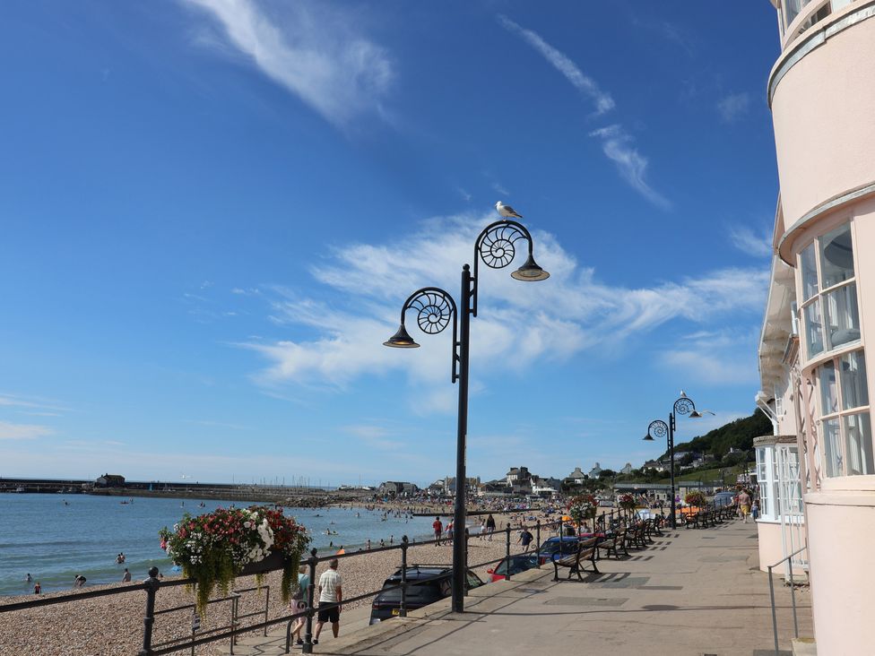 A beach scene with people and benches at Wagtail Cottage in Lyme Regis