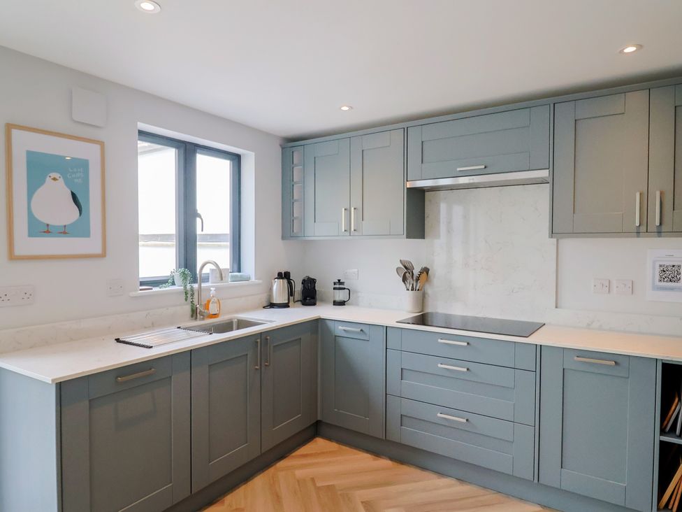 A kitchen with cabinets, sink, and window at Wagtail Cottage in Lyme Regis