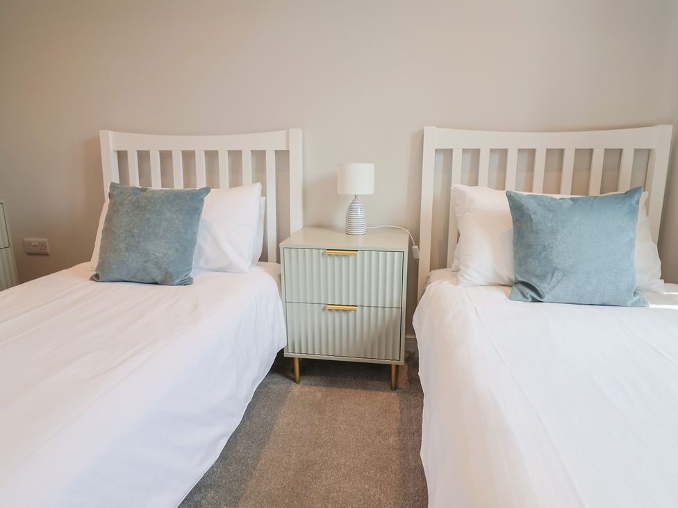 A bedroom with two beds and a nightstand at Wagtail Cottage in Lyme Regis