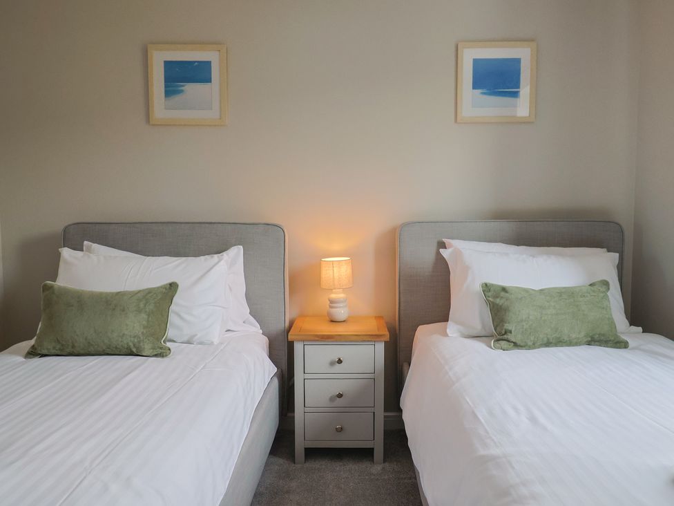 A bedroom with two beds and a nightstand at Wagtail Cottage in Lyme Regis
