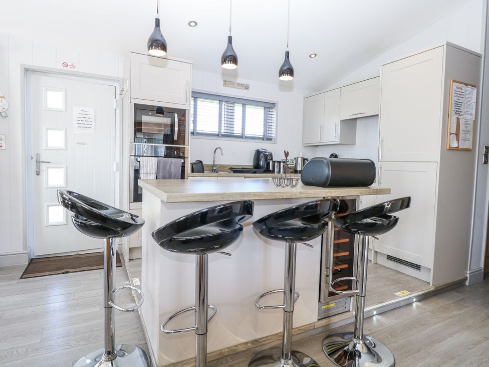 A kitchen with bar stools and modern appliances at Angel Lodge - No 27 Fornham St Genevieve near Bury St Edmunds