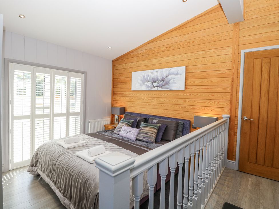 A bedroom with a bed and sliding doors at Angel Lodge - No 27, Fornham St Genevieve near Bury St Edmunds