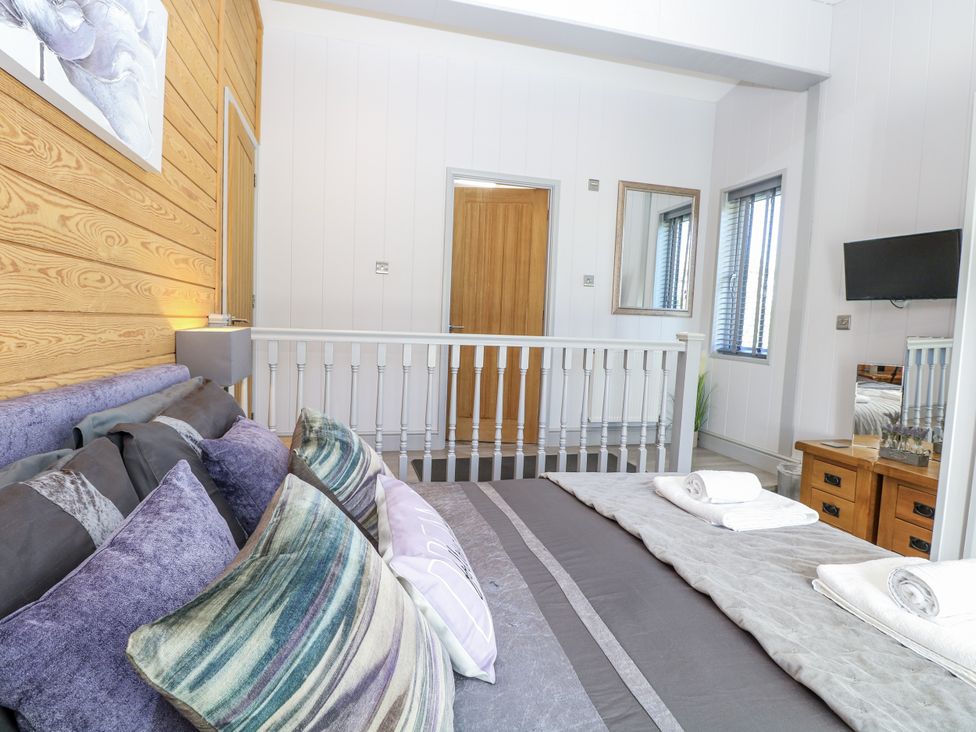 A bedroom with a bed and cushions at Angel Lodge - No 27 in Fornham St Genevieve near Bury St Edmunds
